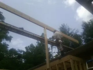 Carpenter setting a ridge beam over a new addition frame — Ice Dam Removal by Roofing Brothers in Staley