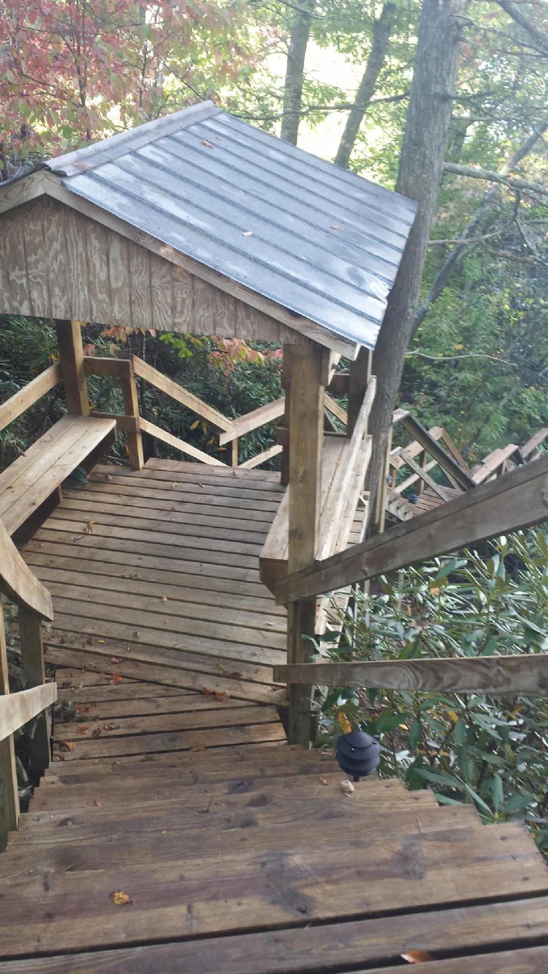 Metal roofed shelter over wooden steps on a wooded walkway — Skylight Repair & Installation work by our crew in Staley